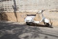 White Classic Vespa scooter stands parked near the concrete old