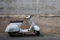 White Classic Vespa scooter stands parked near the concrete old