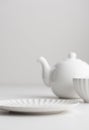 White clean empty tableware: plate and teapot on white background for a dessert