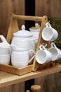 White clean porcelain tea ware on a wooden shelf. Department of crockery, household goods. Kitchen interior design