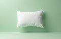 White clean rectangular pillow floats against pale green wall. Smooth studio surface below creates tranquil minimalist Royalty Free Stock Photo