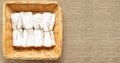 White clean rolled terry towel stack in wicker basket on natural linen sack background. Flat Lay Royalty Free Stock Photo