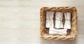 White clean rolled terry towel stack in wicker basket on natural wooden background. Flat Lay