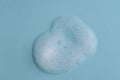 White cleanser foam bubbles on blue background or texture, closeup, top view. Soap suds or foam and bubbles from detergent or Royalty Free Stock Photo