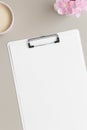 White clipboard mockup with a cup of coffee and oleander on a beige table