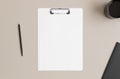 White clipboard mockup with a cup of coffee and workspace accessories on a beige table