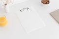 White clipboard mockup wtih a gypsophila in a pot, hazelnuts in a bowl and a juice on a white table