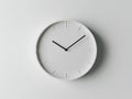 A white clock with black hands on a white wall Royalty Free Stock Photo