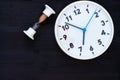 White clock and hourglass on a black wooden background. Top view. Copyspace. Education or business concept Royalty Free Stock Photo