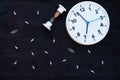 White clock, hourglass and pins on a black wooden background. Top view. Copyspace. Education or business concept Royalty Free Stock Photo