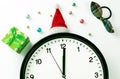 A white clock in a red Santa hat shows five seconds to midnight, on a white background with Christmas decorations. Countdown to Royalty Free Stock Photo