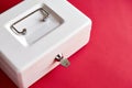 White closed cashbox with key on pink background