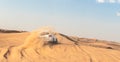 White closed jeep Toyota extremely drives through the sandy desert near Dubai city, United Arab Emirates