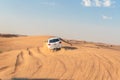 White closed jeep Toyota extremely drives through the sandy desert near Dubai city, United Arab Emirates