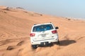 White closed jeep Toyota extremely drives through the sandy desert near Dubai city, United Arab Emirates