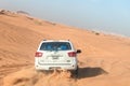 White closed jeep Toyota extremely drives through the sandy desert near Dubai city, United Arab Emirates