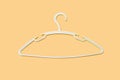 A white clothes hanger is empty without clothes on orange background close-up Royalty Free Stock Photo