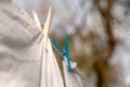 White clothes hung out to dry on a washing line and fastened by the clothes pegs in the bright warm sunny day. Blurred garden at Royalty Free Stock Photo