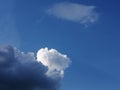 A white cloud and dark cumulus floating against a clear blue sky