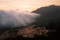 White cloud of mist entering and covering a rice field landscape in a valley between mountains at sunset. Royalty Free Stock Photo