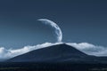 A white cloud in the shape of a crescent moon on a dark blue sky with a black mountain background, clouds are in front of it, Royalty Free Stock Photo