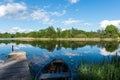 White clouds on the blue sky over blue lake with boats and board Royalty Free Stock Photo