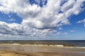 White clouds on blue sky over calm Baltic sea with sunlight reflection in sea. Royalty Free Stock Photo