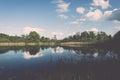 White clouds on the blue sky over blue lake - retro vintage effect Royalty Free Stock Photo