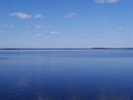 White clouds in the blue sky reflected on the surface of calm water Royalty Free Stock Photo