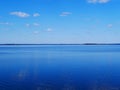 White clouds in the blue sky reflected on the surface of calm water Royalty Free Stock Photo