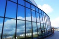 White clouds and clear blue sky reflecting in glass facade of modern office building Royalty Free Stock Photo