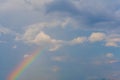 White clouds and colorful rainbow against blue sky