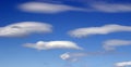 White clouds like UFOs in the blue sky. summer Sunny bright day. Blue background.