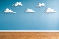 White clouds painted on blue wall in empty room with parquet floor and copy space