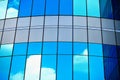 White clouds reflect sunlight on tall glass blue abstract crop of modern office skyscraper texture and bacgound. Royalty Free Stock Photo