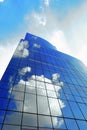 White clouds reflect sunlight on tall glass blue abstract crop of modern office skyscraper texture and bacgound. Royalty Free Stock Photo