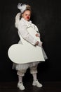 White clown woman with white empty heart banner on black background Royalty Free Stock Photo