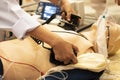 A white coat physician perform defibrillationon a doll during AC ACLS training