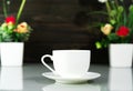Coffee cup and Artificial flower vase bouquet over table Royalty Free Stock Photo