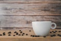 A white coffee cup with coffee beans are placed on a wooden plate and on a wooden background Royalty Free Stock Photo