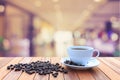 White coffee cup and coffee beans on wood table with blurred bac Royalty Free Stock Photo