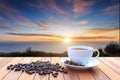 White coffee cup and coffee beans on wood table and view of suns Royalty Free Stock Photo