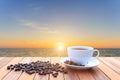 White coffee cup and coffee beans on wood table and view of suns Royalty Free Stock Photo