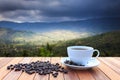 White coffee cup and coffee beans on wood table and view of suns Royalty Free Stock Photo