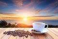 White coffee cup and coffee beans on wood table and view of suns Royalty Free Stock Photo