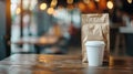 White coffee cup and craft paper bag mockup on cafe interior table with blurred background Royalty Free Stock Photo