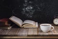 White coffee cup with dark black coffee And old books And the clock is arranged on an old wooden table and a black wooden wall Royalty Free Stock Photo