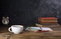 White coffee cup with dark black coffee And old books And the clock is arranged on an old wooden table and a black wooden wall Royalty Free Stock Photo