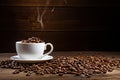 A white coffee cup full of coffee beans spilling out on a wood background Royalty Free Stock Photo