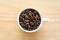 White coffee cup full of coffee beans on wooden background Royalty Free Stock Photo